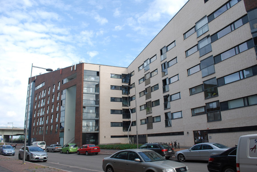 5 kerroksinen vaalesävyinen tiiliverhoiltu kerrostalo.