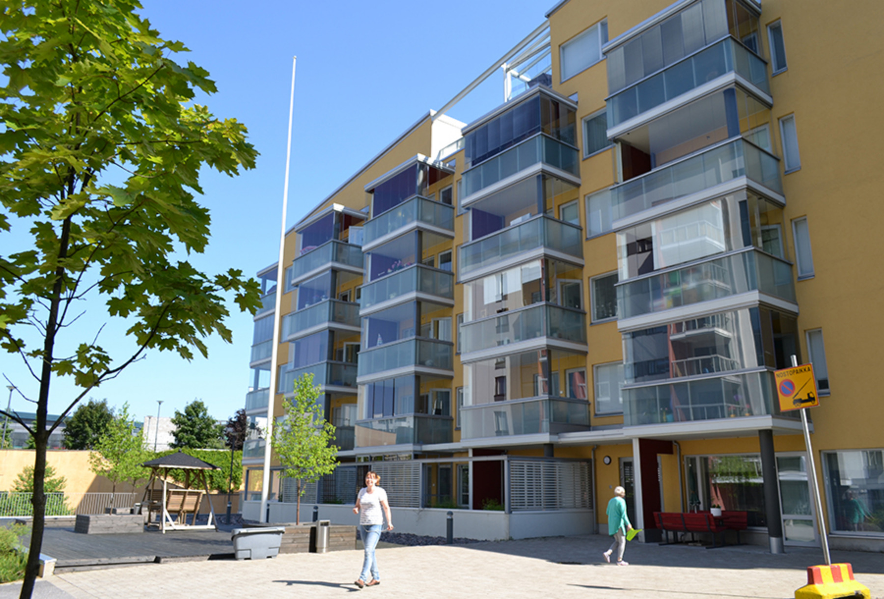 Nelikerroksinen keltasävyinen kerrostalo, jossa lasitetut parvekkeet