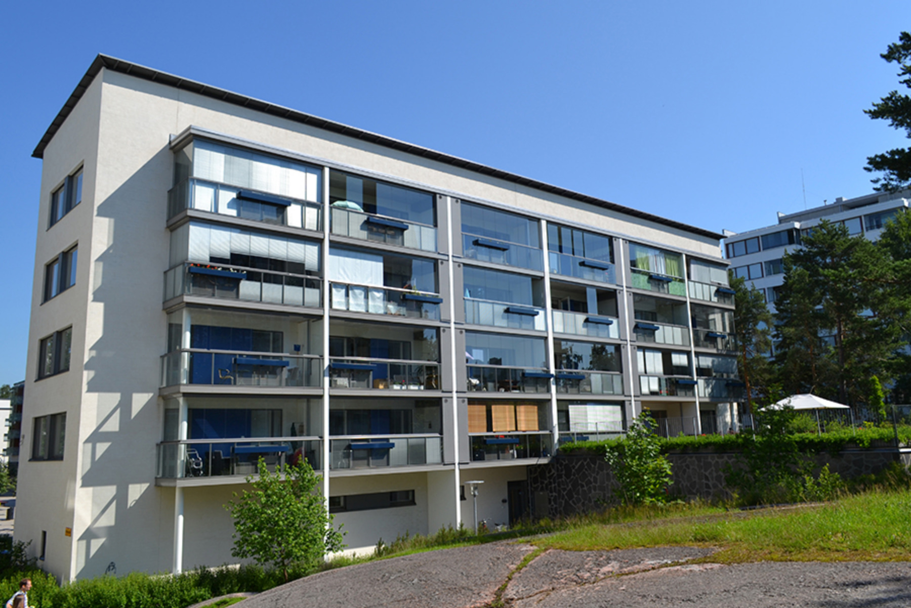 4 kerroksinen vaaleasävyinenkerrostalo, jossa tummat, lasitetut parvekkeet